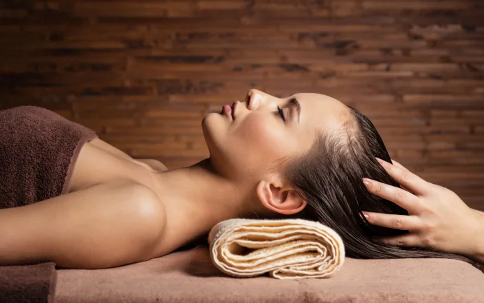 Client enjoying a relaxing head massage at a salon backwash during a luxury hair treatment focused on wellbeing.