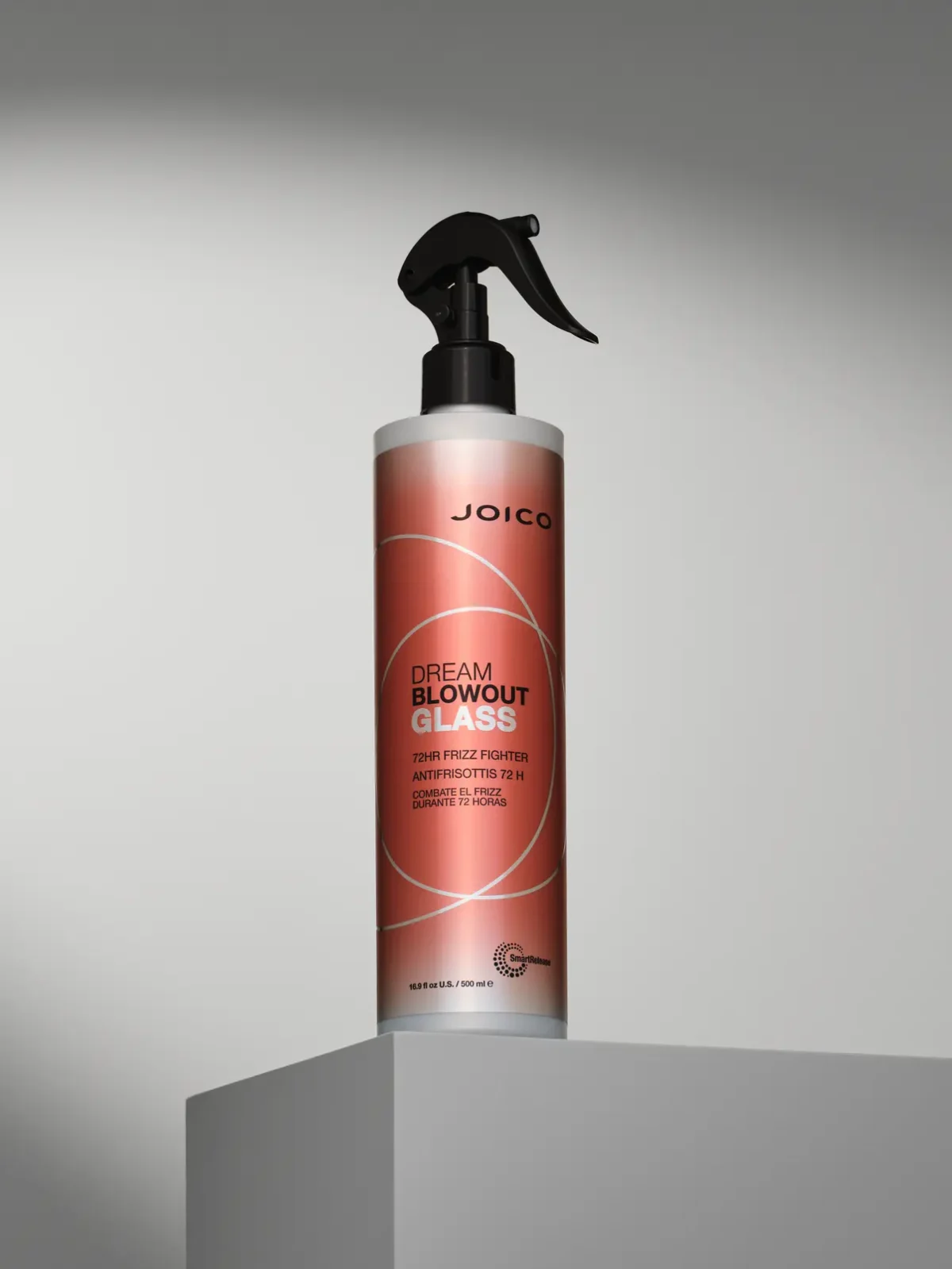 JOICO Dream Blowout Glass frizz-fighting spray bottle with on a stand, designed for smooth, glossy blow-dry results.