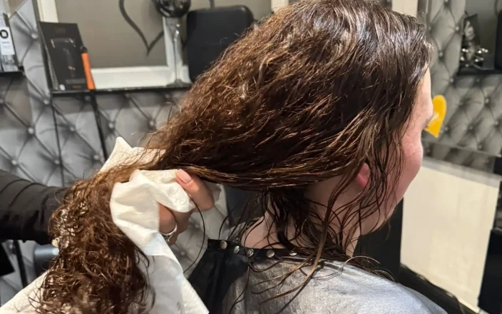 A hairdresser dries a client's hair with an Enki Towel.