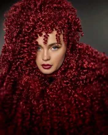 Model with long, red flowing curls all over her head and shoulders from the Marlene Lamont Conviction Collection.