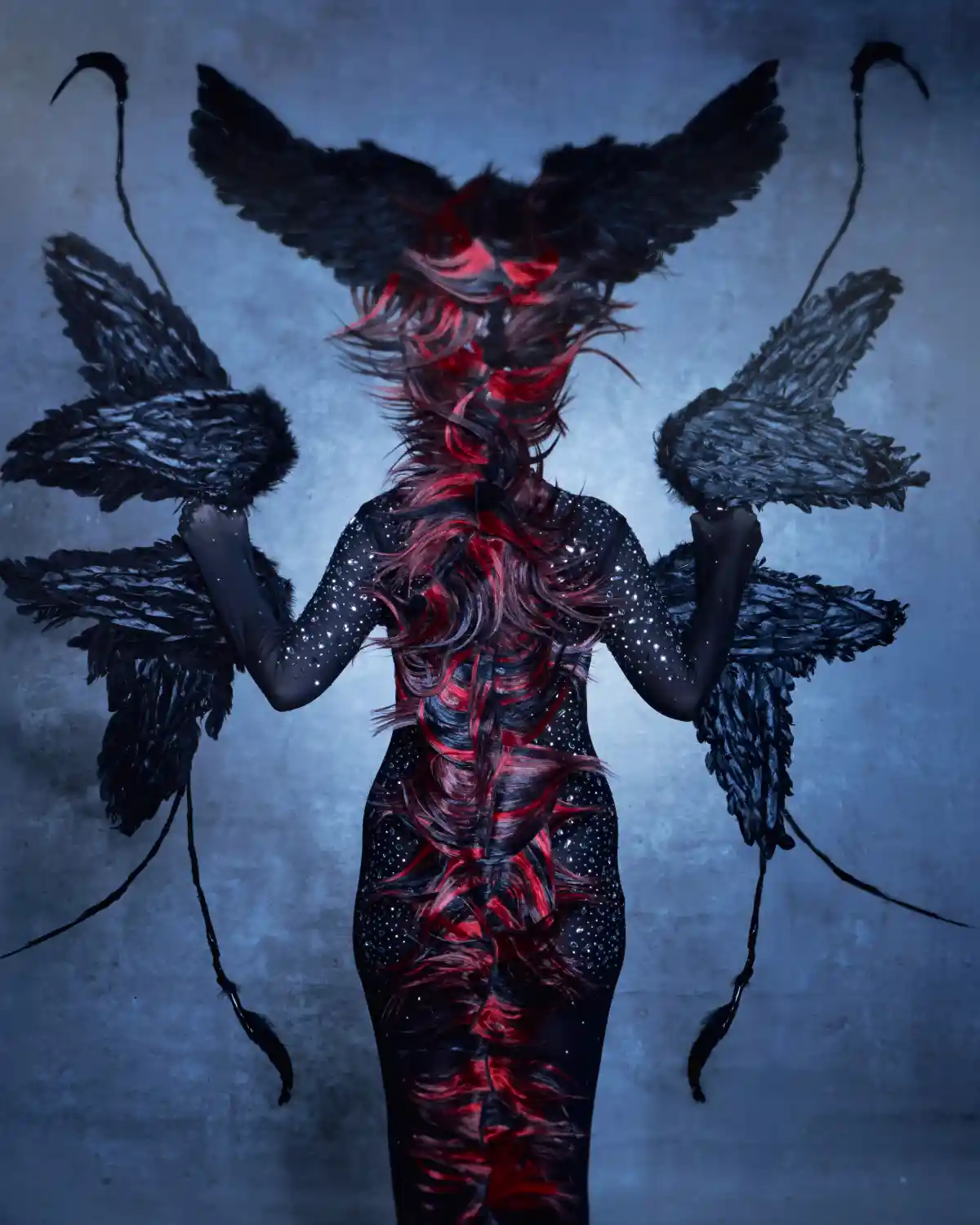 Model with her back facing the camera showing red and black headdress from the collection 'ANGELS’ by William and Norma Gray.