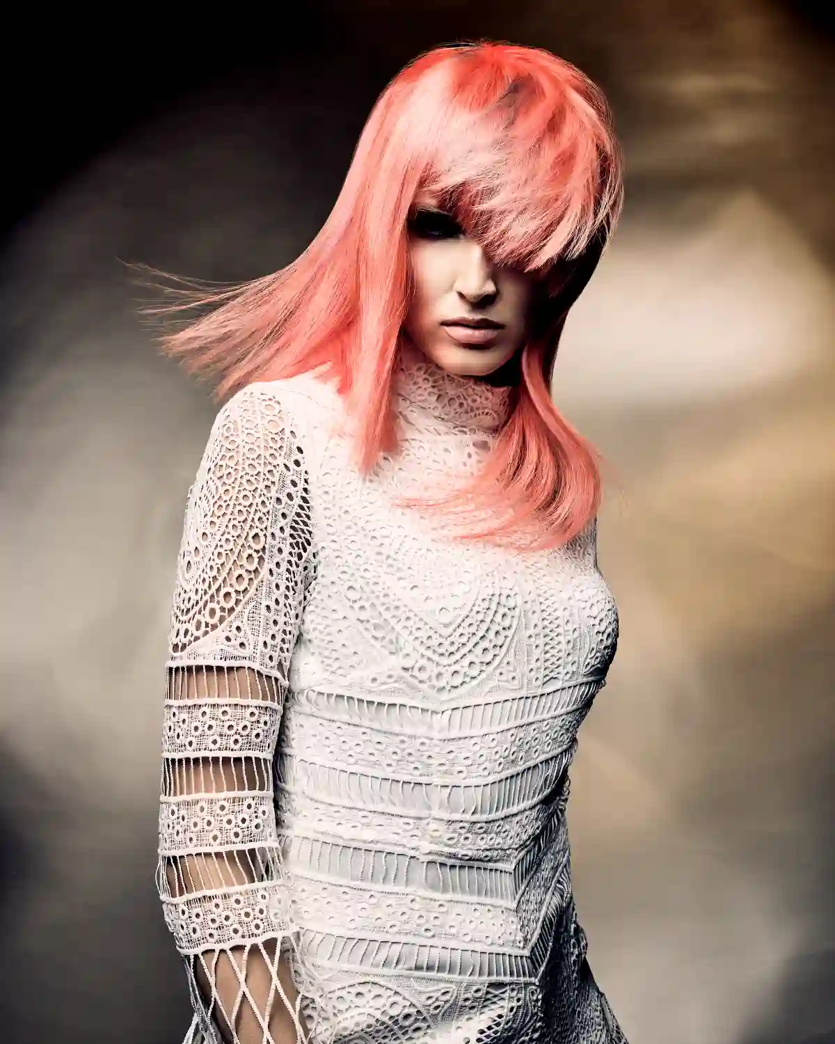 Tempest Collection by Alex Thaddeus featuring a vibrant coral pink hairstyle with full fringe and flowing layers, inspired by atmospheric movement.