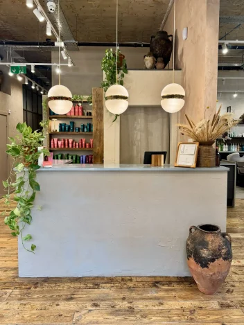 Butchers Salon reception featuring reclaimed wood, indoor plants, natural décor and sustainable salon design with Aveda retail display.