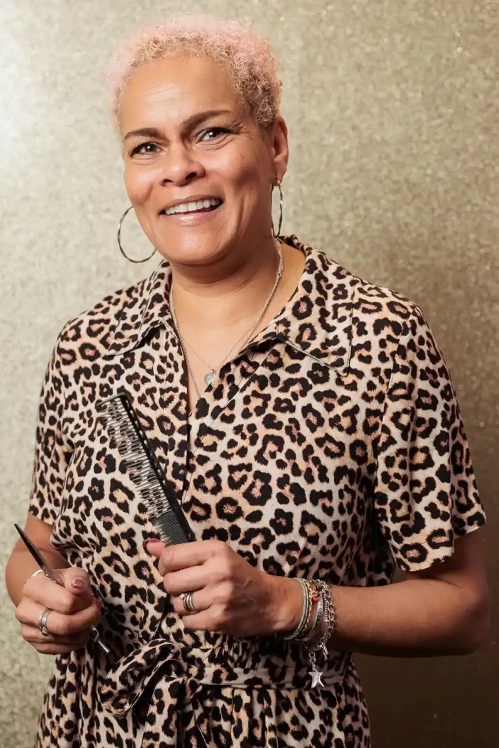 Hairstylist Chris Grimley wearing a leopard print blouse and holding hair tools.