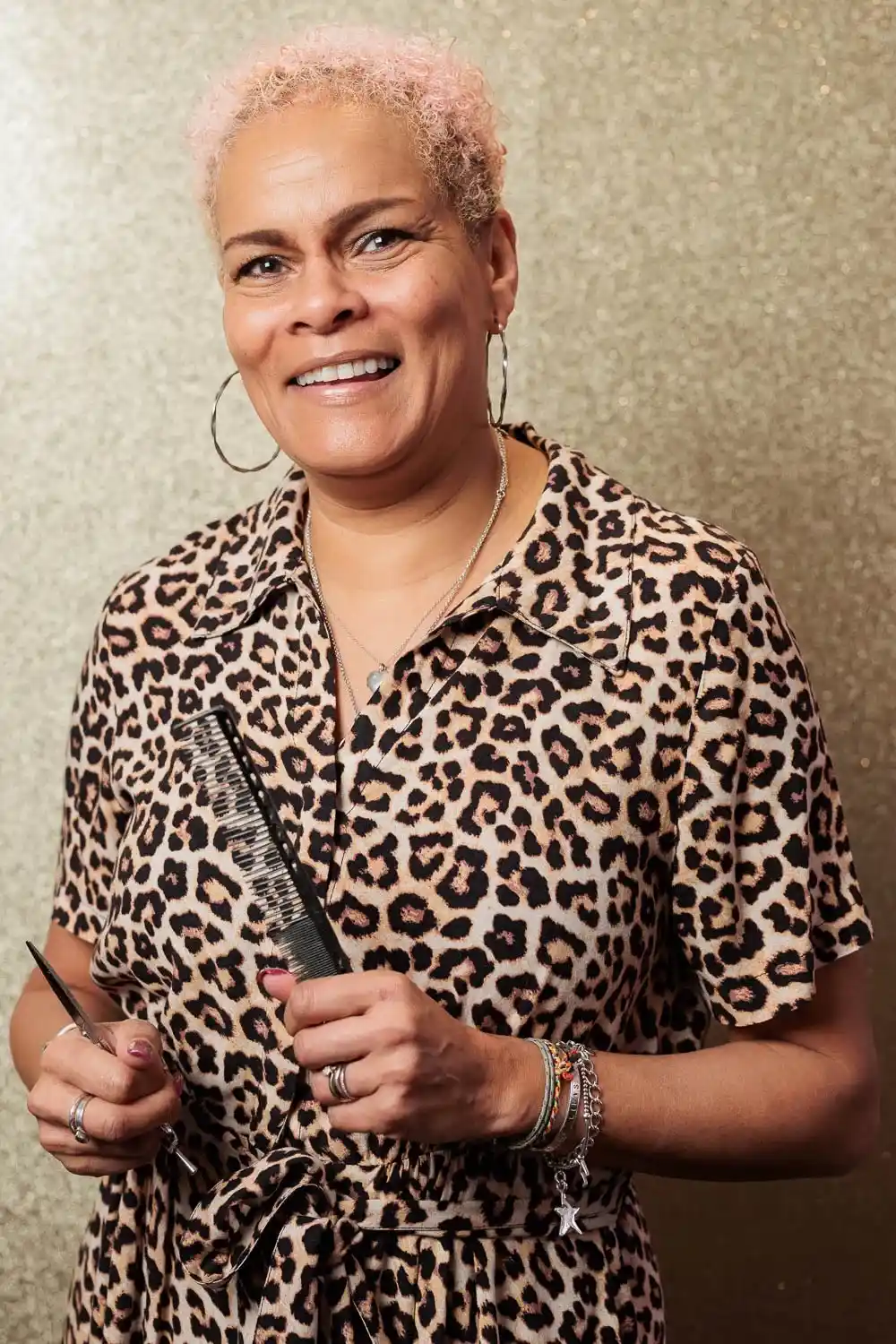 Hairstylist Chris Grimley wearing a leopard print blouse and holding hair tools.
