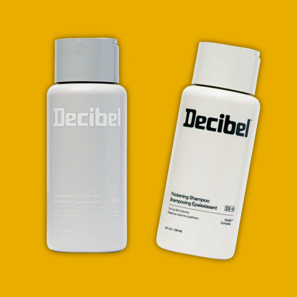 A bottle of Decibel Shampoo and a bottle of Decibel Conditioner on a yellow background.