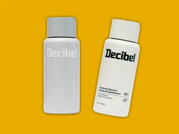 A bottle of Decibel Shampoo and a bottle of Decibel Conditioner on a yellow background.
