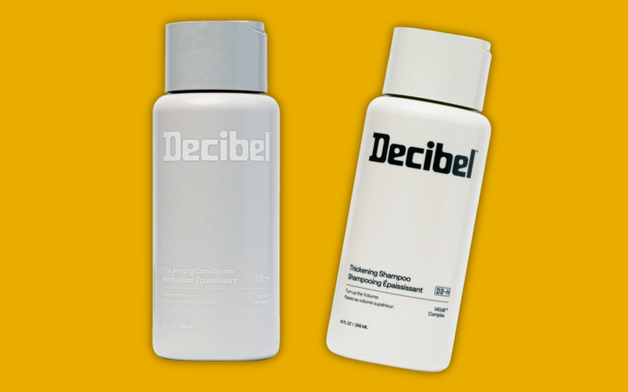 A bottle of Decibel Shampoo and a bottle of Decibel Conditioner on a yellow background.