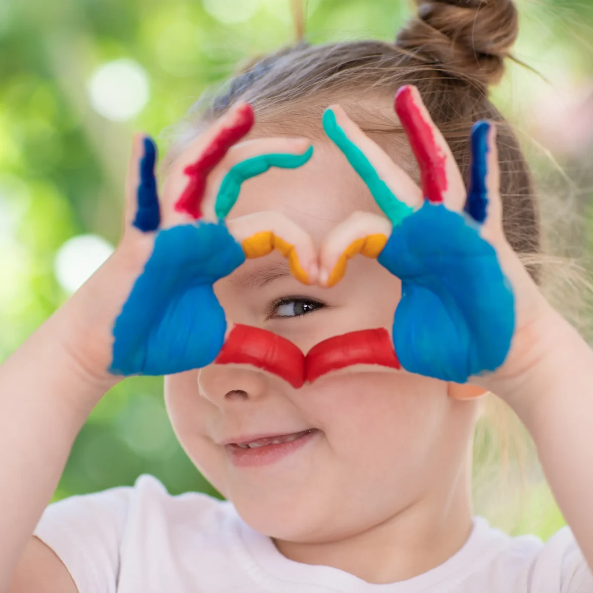 Happy child smiles and makes a kind love heart shape.