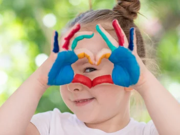 Happy child smiles and makes a kind love heart shape.