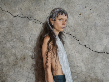 Model at Copenhagen Fashion Week with tinsel in her hair against a concrete backdrop.