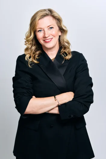 Kathleen Mitchell wears a black outfit against a white backdrop.
