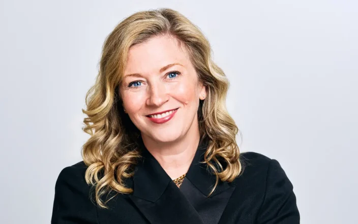 Kathleen Mitchell wears a black outfit against a white backdrop.