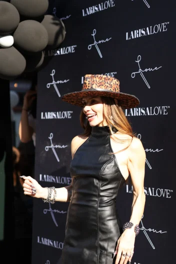 Larisa Love stands in front of an advertising board.