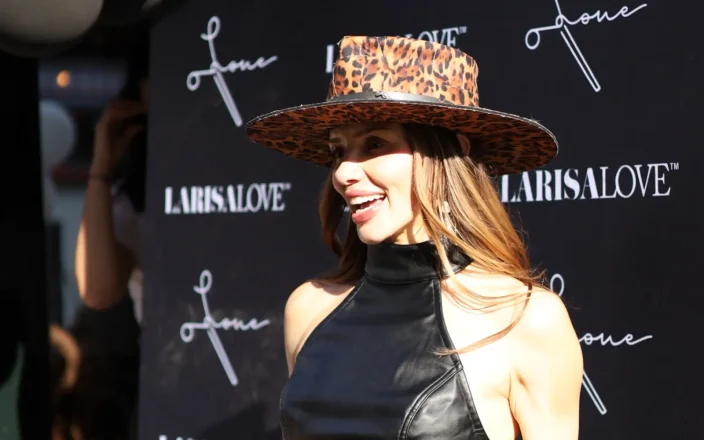 Larisa Love stands in front of an advertising board.