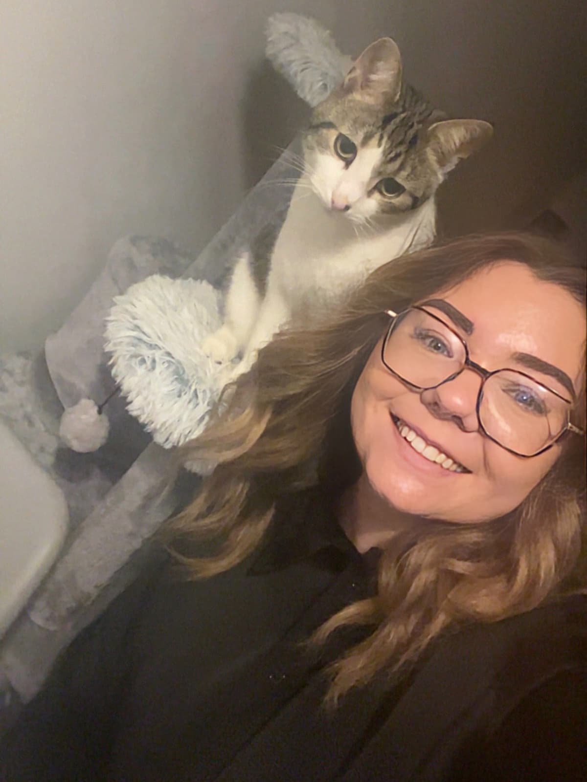 Hairdresser Lauren stands in front of her pet cat that she was reunited with by the Denman team.