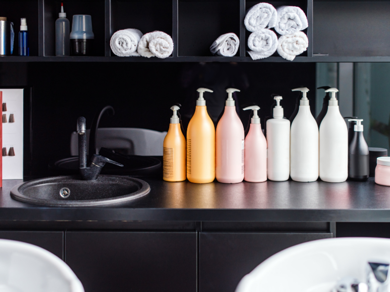 Hair products and tools lined up on a salon's backwash.