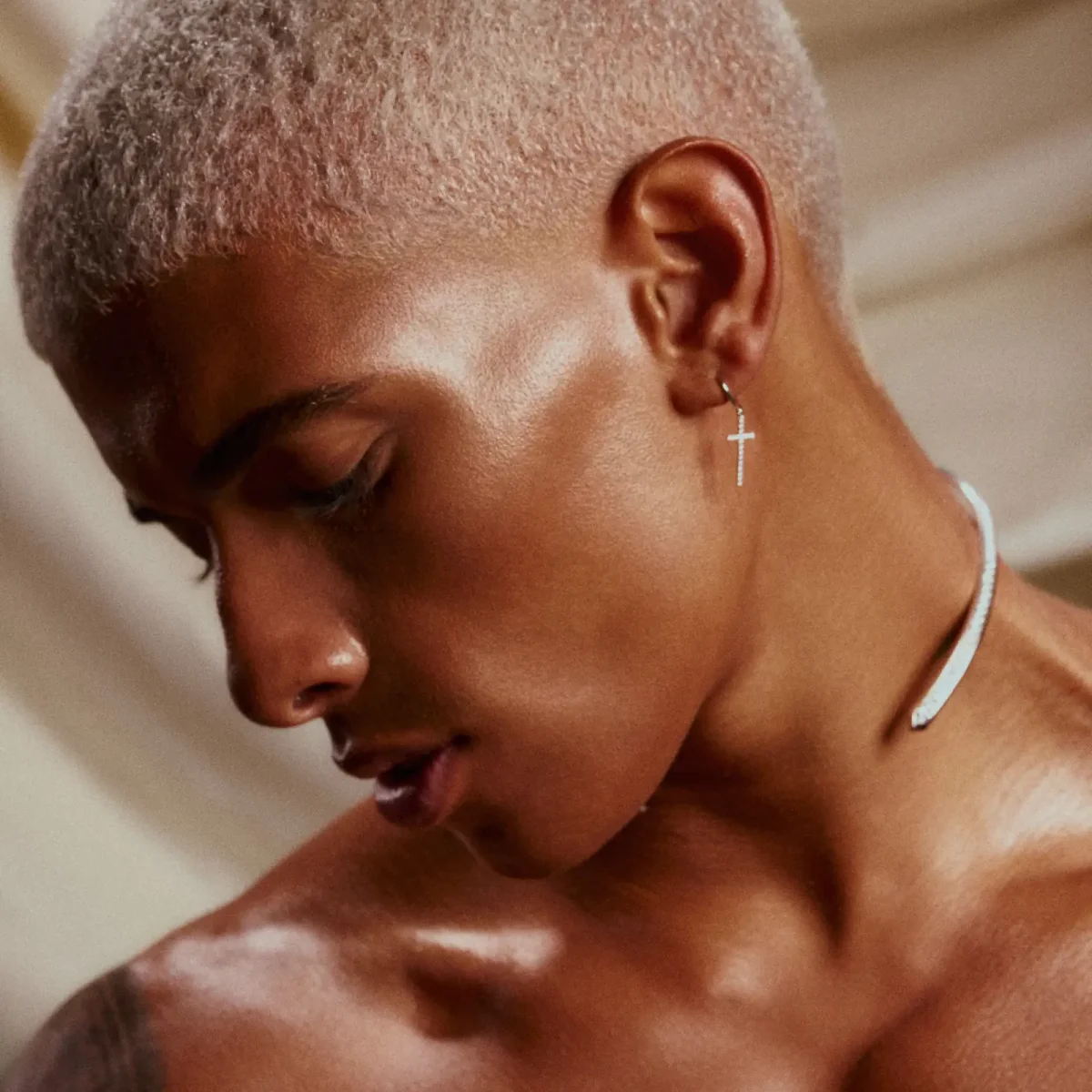 Model with blonde buzz cut looks down.