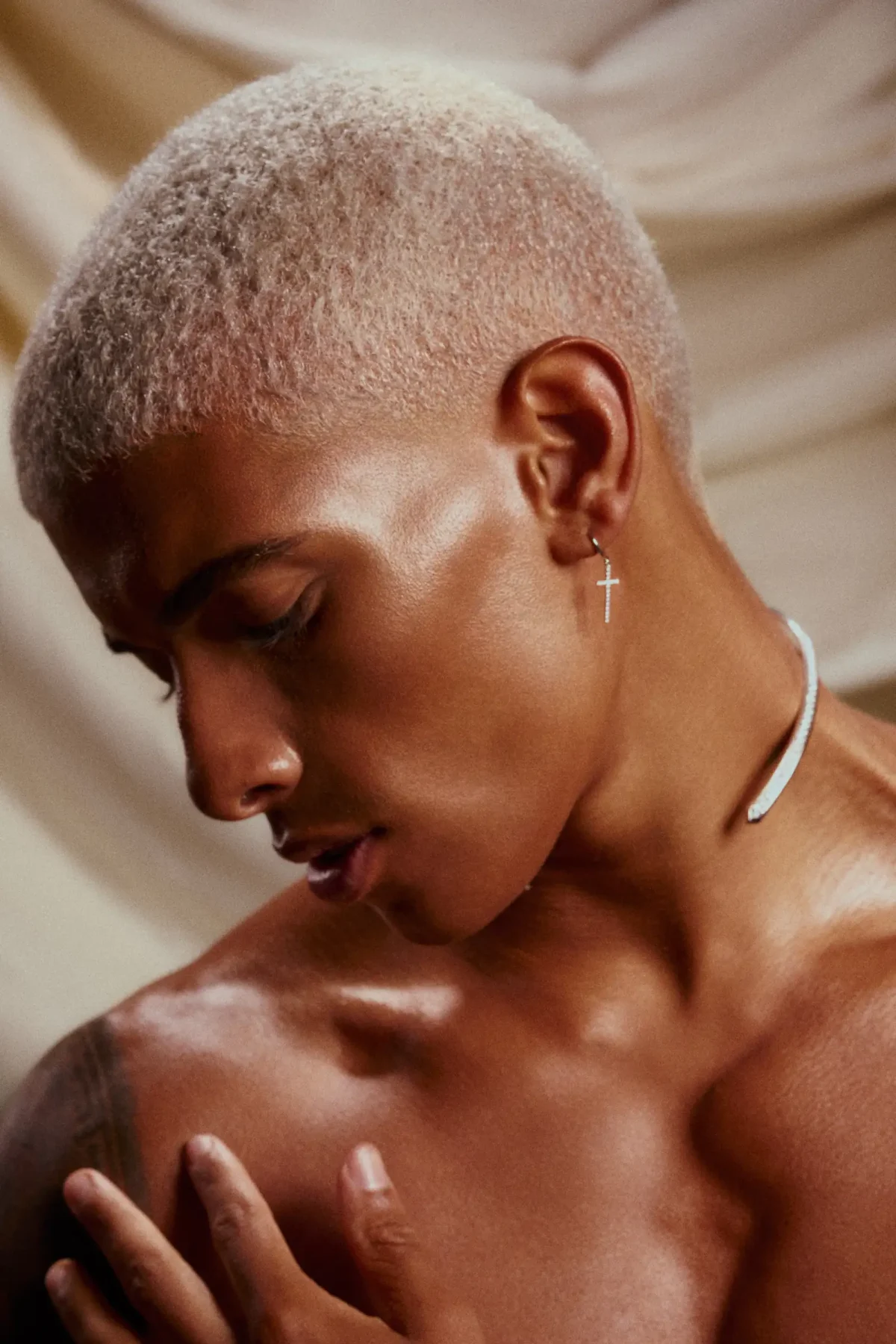 Model with blonde buzz cut looks down.