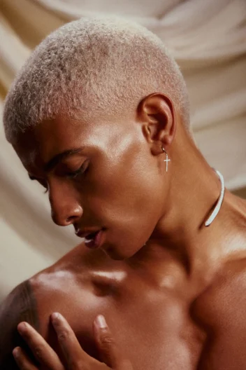 Model with blonde buzz cut looks down.