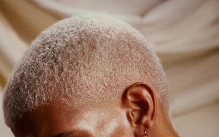 Model with blonde buzz cut looks down.