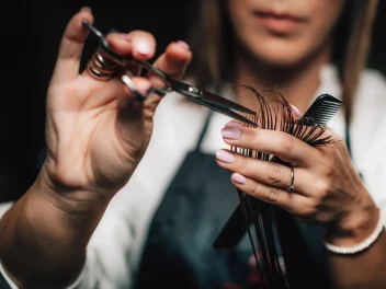A hairdresser cuts a client's hair highlighting NHBF Welcoming Technical Education Plans.