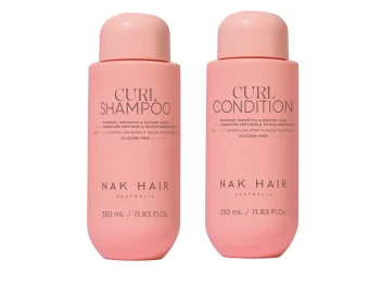 Pink branded bottles of Nak Hair Curl Definition shampoo and conditioner on a white background.
