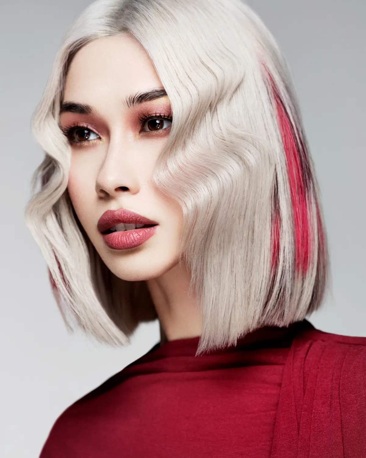 Platinum blonde blunt bob with Sriracha red peekaboo highlights from Roar Hair & Beauty's AW26 hair trend predictions.
