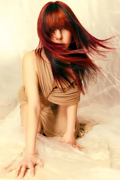 Model with long, flowing dark red and black hair swept across the face from the Solstice collection by Safy Burton, featuring dramatic movement and rich luminous tones inspired by the shifting colours of sunrise and sunset skies.