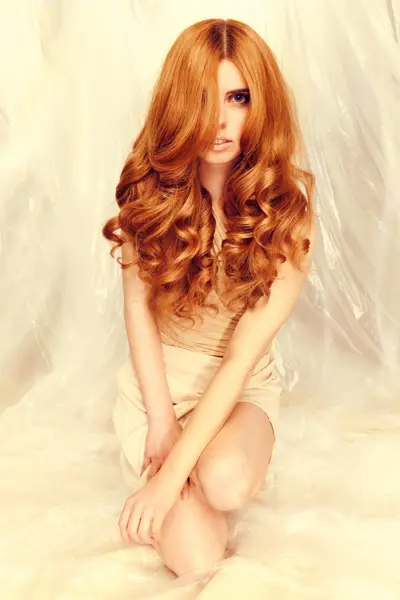 Model with long, voluminous copper-red curls and soft waves from the Solstice collection by Safy Burton, inspired by the shifting tones of sunrise and sunset skies with fluid movement, softness and luminous warm colour.