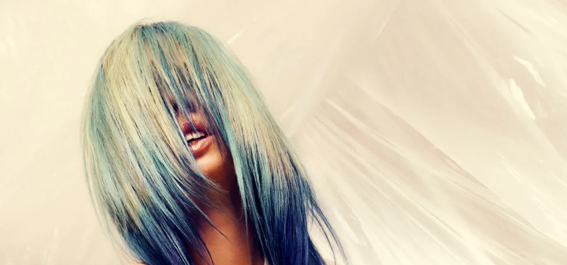 Model with long, flowing pale blonde hair featuring blue and teal tones from the Solstice collection by Safy Burton, with hair covering the face and creating a soft, fluid effect inspired by the shifting colours of sunrise and sunset skies.