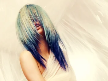 Model with long, flowing pale blonde hair featuring blue and teal tones from the Solstice collection by Safy Burton, with hair covering the face and creating a soft, fluid effect inspired by the shifting colours of sunrise and sunset skies.