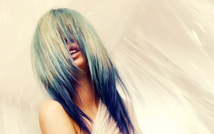Model with long, flowing pale blonde hair featuring blue and teal tones from the Solstice collection by Safy Burton, with hair covering the face and creating a soft, fluid effect inspired by the shifting colours of sunrise and sunset skies.