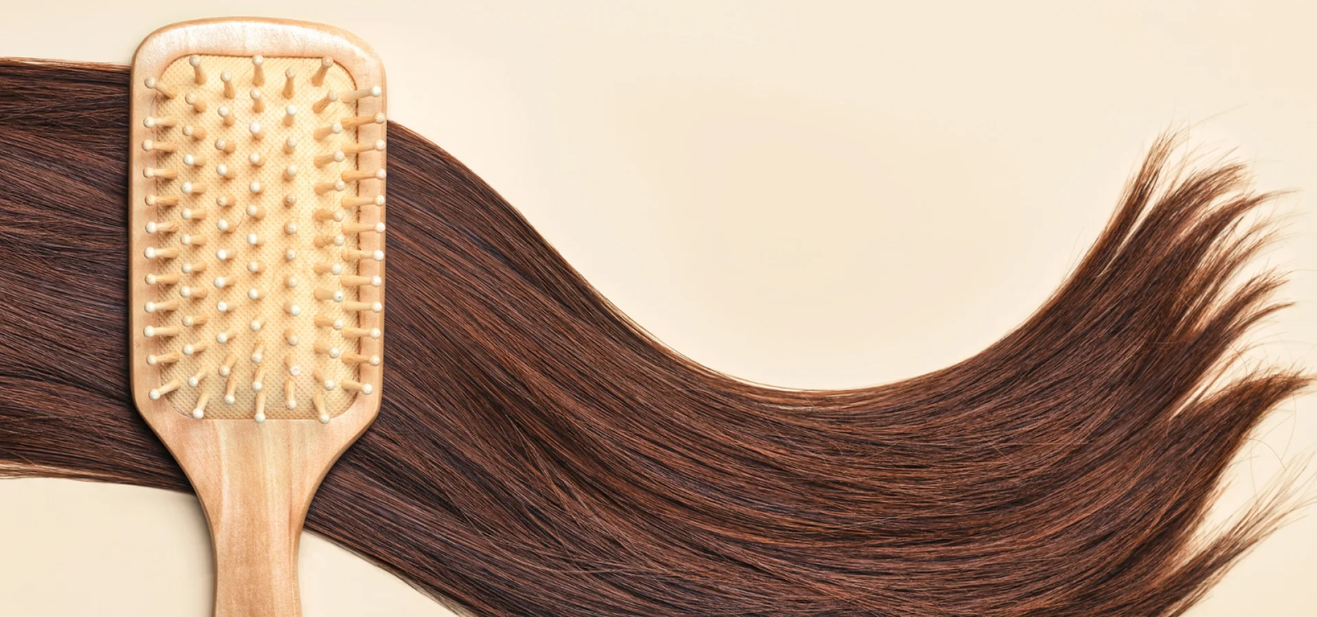 Long brown hair on a cream background with a hair brush.