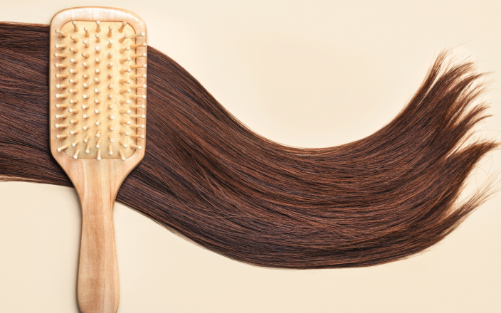 Long brown hair on a cream background with a hair brush.
