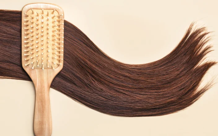 Long brown hair on a cream background with a hair brush.