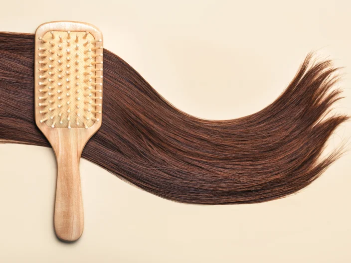 Long brown hair on a cream background with a hair brush.