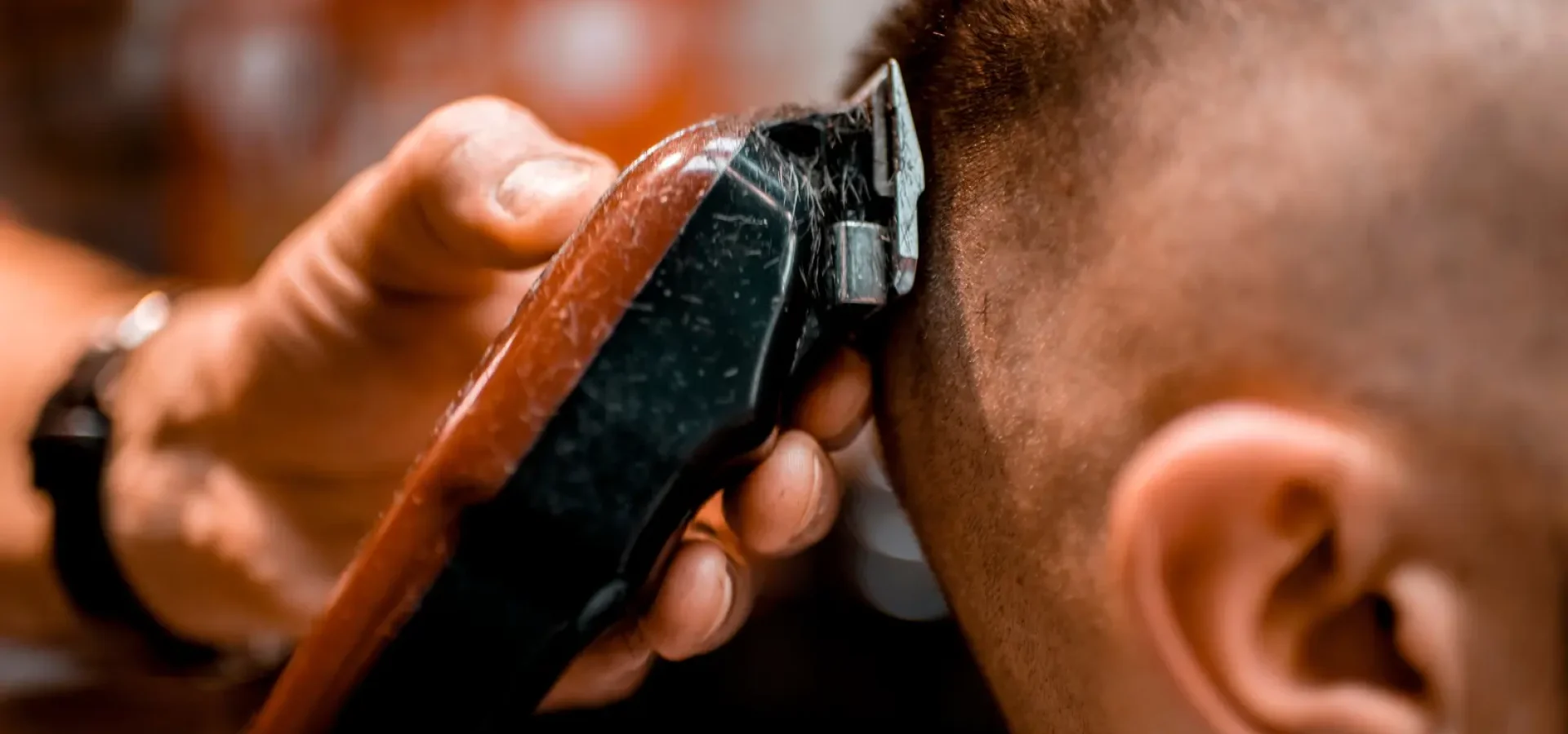 A hand holding an electric razor shaves a buzz cut on a model.