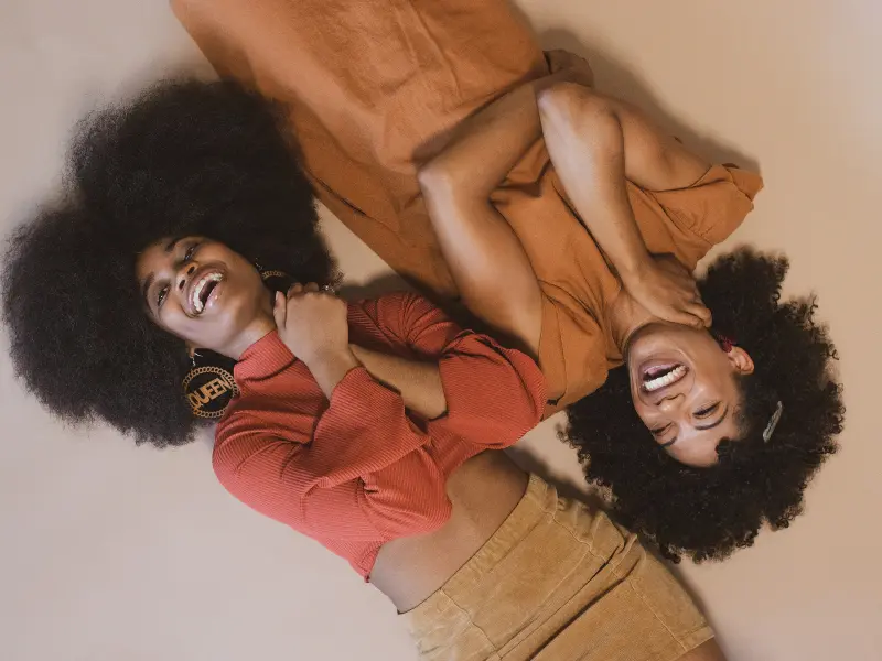 Two curly hair models lie side by side.