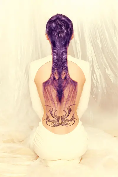 Woman with long purple-toned hair styled into an intricate flowing design down her back, from the Solstice collection by Safy Burton, inspired by sunrise and sunset skies with fluid shapes and luminous atmospheric colour.