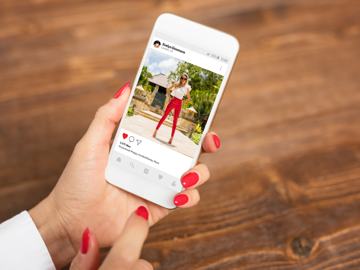 Hand holds a mobile phone with a photo of an insta Influencer on the screen