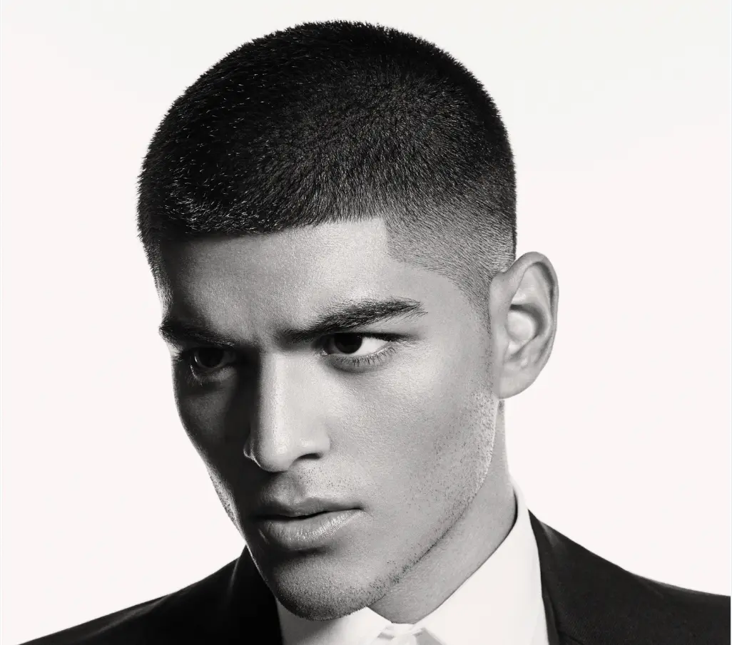 Black and white image of a male model with a buzz cut hair style.