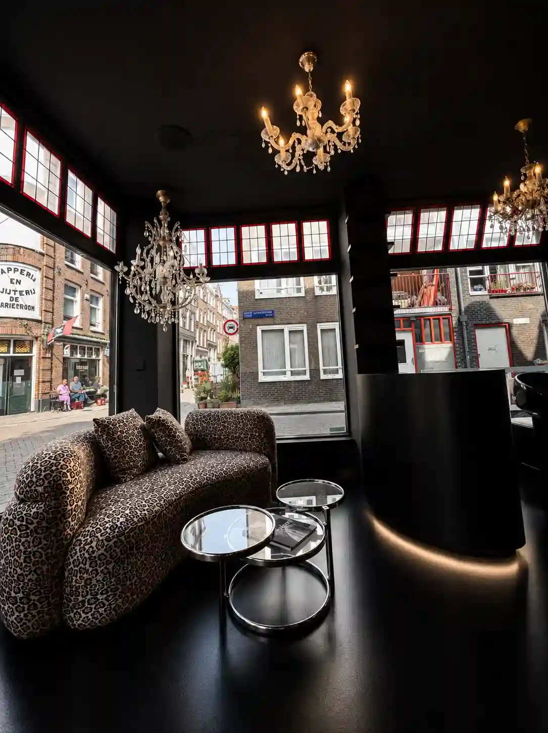 A sofa by a window with chandeliers overhead in the Amsterdam salon.