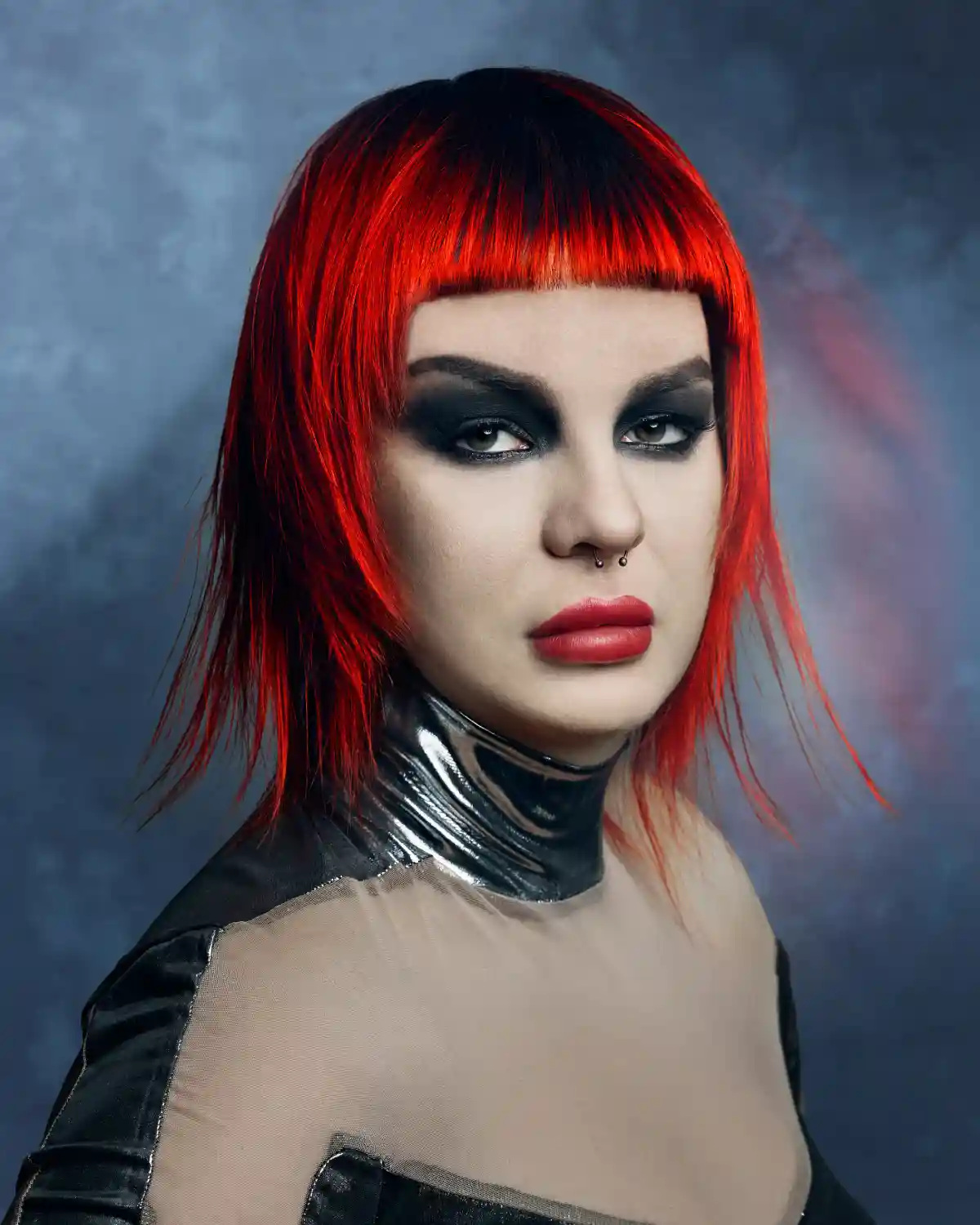PRISM by William and Bianca Gray featuring a bold red bob with blunt fringe, dark roots and vibrant colour contrast.
