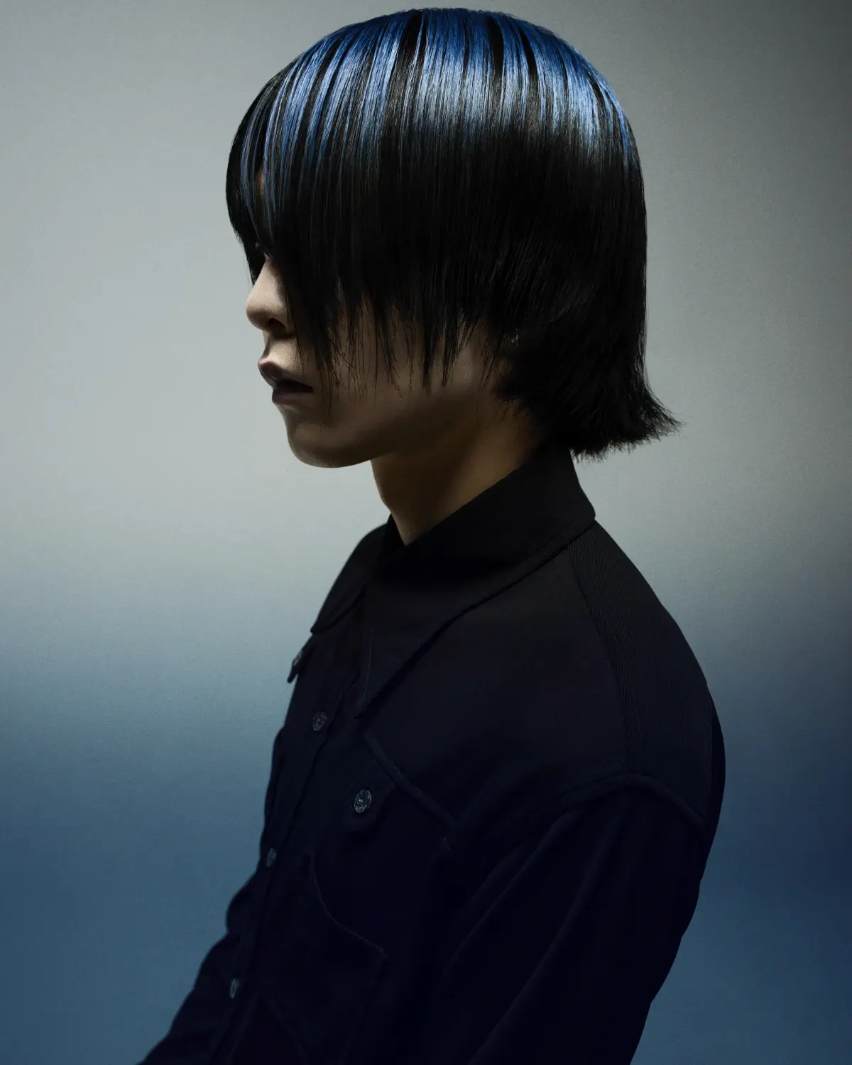 Model with short black hair with blue flecks exploring refined simplistic beauty with the Eclipse collection by Marlon Hawkins.