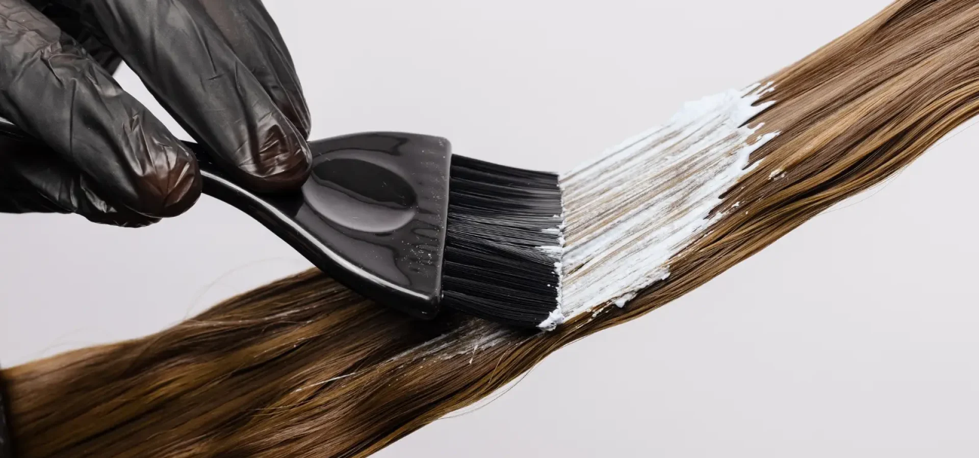A hand paints hair with dye.