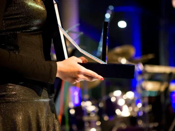 Hands holding an award on a stage.