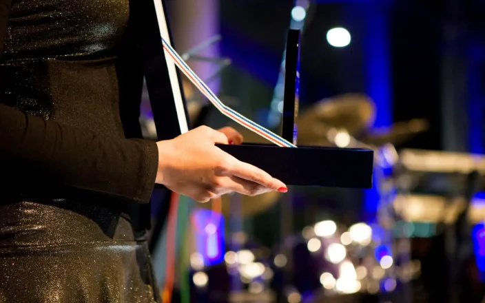 Hands holding an award on a stage.
