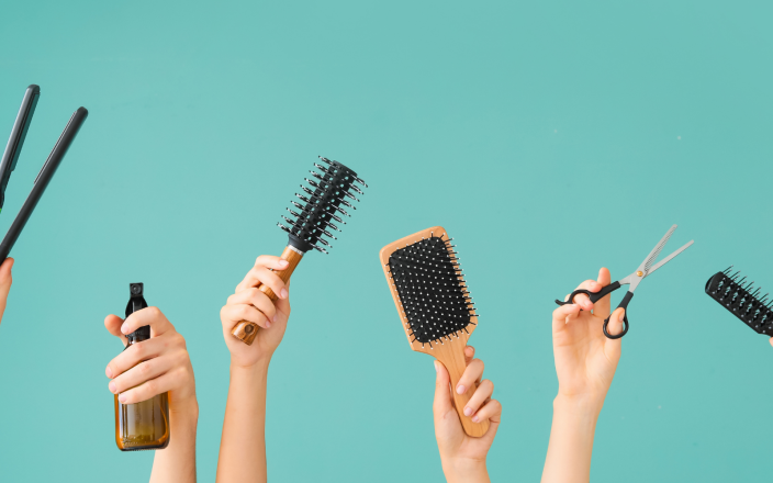 Many hands holding hair tools.