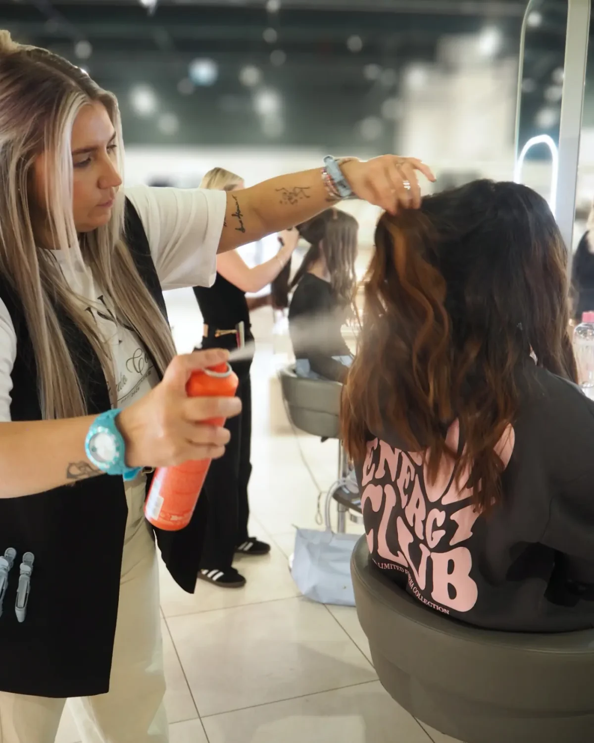Hairdresser sprays a model's hair.